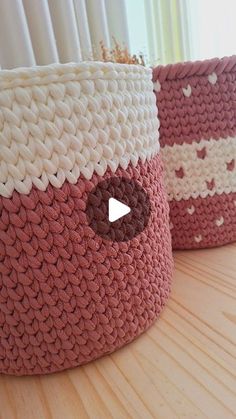 two crocheted baskets sitting on top of a wooden table next to a window