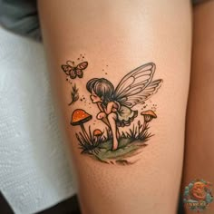 a woman's thigh with a fairy tattoo on her leg and mushrooms in the background