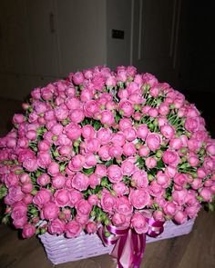 a basket filled with pink flowers on top of a wooden floor