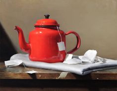 a red teapot sitting on top of a table next to a piece of paper