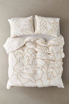 an image of a bed with white sheets and gold embroidered leaves on the comforter