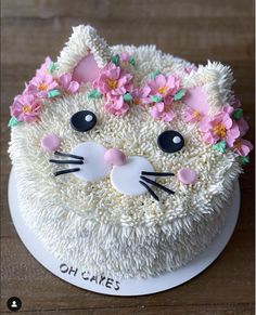 a cake decorated with white frosting and pink flowers on top of a wooden table