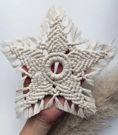 a hand holding an ornament made out of beads and tassels on a white background