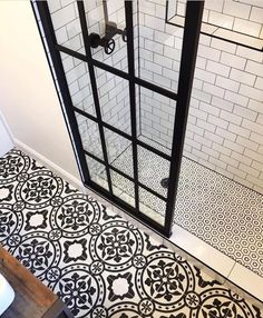 a bathroom with black and white tile on the floor next to a glass shower door