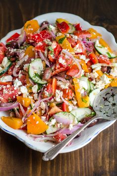 a salad with tomatoes, cucumbers, and other vegetables on a white plate