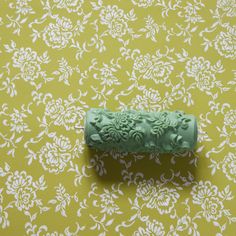 a green object sitting on top of a yellow and white floral wallpaper covered floor