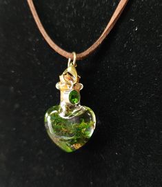 a green heart shaped glass pendant on a leather cord