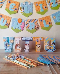 a table topped with lots of paper cutouts next to wooden letters and magnets