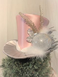 a pink top hat with silver feathers and a feathered ornament on it