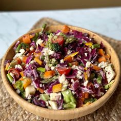 a wooden bowl filled with salad on top of a table