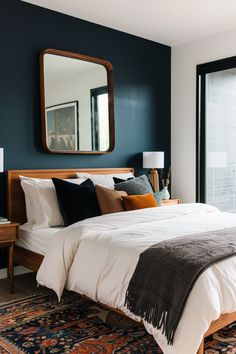 a bedroom with blue walls and white bedding has a large mirror on the wall