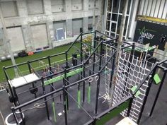 an indoor climbing gym in a building with green and black ropes on the floor, surrounded by concrete walls