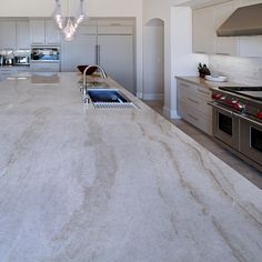 a large kitchen with marble counter tops and stainless steel ovens in the center island