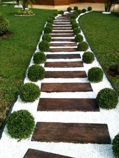 a garden path made out of wood and white gravel with grass growing on the sides