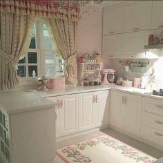 a kitchen with white cabinets and pink rugs on the floor, along with curtains