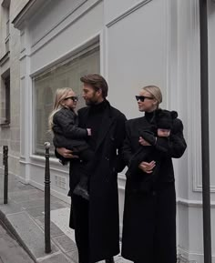 a man and two women are walking down the street while holding their baby daughter in her arms