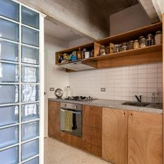 an empty kitchen with wooden cabinets and glass doors on the wall, next to a stainless steel stove top oven