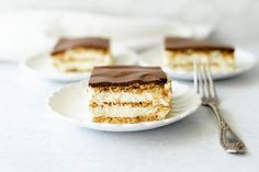 three pieces of cake sitting on top of a white plate next to a silver fork