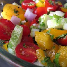 a salad with tomatoes, cucumbers, and other vegetables in a glass bowl