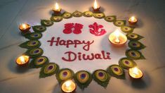 happy diwali with lit candles and peacock feathers in the center on a white surface