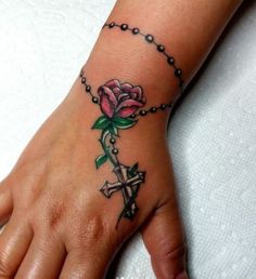 a woman's hand with a cross and rose tattoo on it