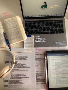 an open laptop computer sitting on top of a desk next to a book and headphones