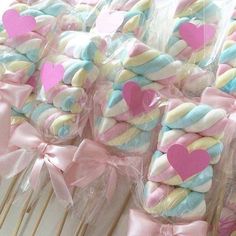 some lollipops wrapped in pink, blue and yellow with hearts on them