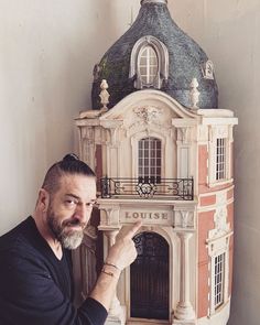 a man standing in front of a doll house