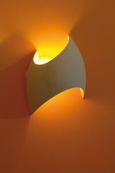 a light that is on the side of a wall with an orange glow behind it