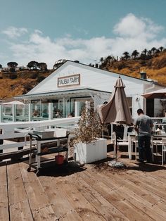 people sitting at tables on a wooden deck