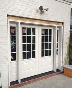 a white building with two doors and windows on the side of it, next to a potted planter