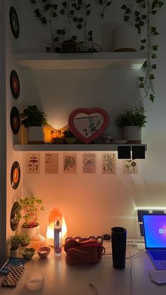 a laptop computer sitting on top of a desk next to a lamp and potted plants