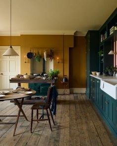 a kitchen with wooden flooring and green cabinets in the center, next to a dining table