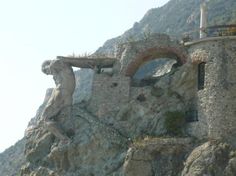 an old stone building sitting on the side of a mountain