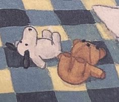 two stuffed animals laying on a checkered blanket