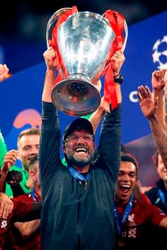 the liverpool manager lifts the trophy as he celebrates with his team