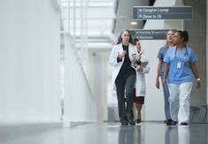 three women in scrubs are walking down the hall