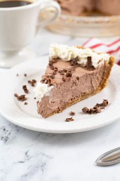 a slice of chocolate pie on a white plate with a cup of coffee in the background