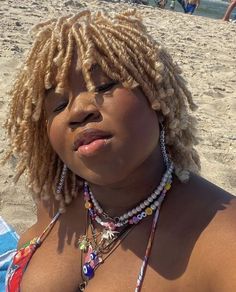 a woman with blonde dreadlocks sitting on the beach