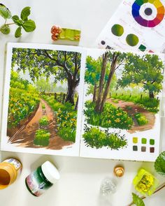 an open book with watercolors and paints on the table next to it is a tree