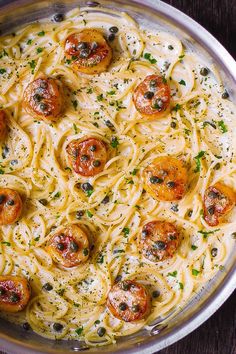 a pan filled with pasta topped with tomatoes and olives