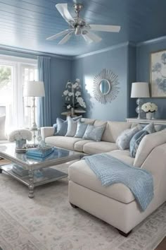 a living room with blue walls and white furniture in the center, along with a ceiling fan