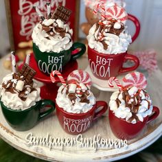 hot cocoa and marshmallows in red mugs with candy canes on top