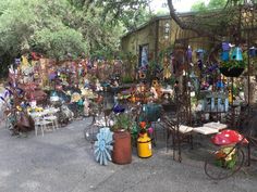 an outdoor market with lots of tables and chairs covered in plants, flowers and other things