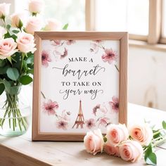 pink roses are sitting on a table next to a framed sign