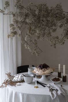 a table topped with plates and bowls filled with desserts next to a tree branch