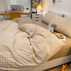 an unmade bed with brown and white checkered comforter on top of it