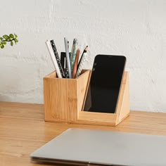 a wooden desk with a laptop and pen holder