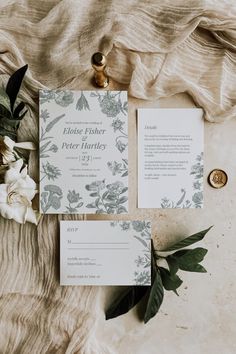 the wedding stationery is laid out with flowers and greenery