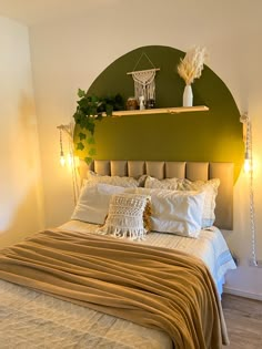 a bed with pillows and blankets on top of it next to a green headboard